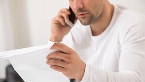 Mann telefoniert mit einem Brief in der Hand