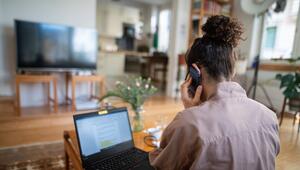 Eine Frau telefoniert vor einem geöffneten Laptop zu Hause