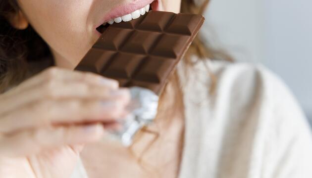 Frau beißt genüsslich in eine Tafel Schokolade