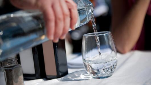 Mann gießt Wasser in ein Glas