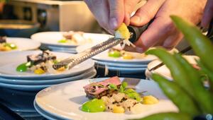 Koch reibt Zesten der Zitrusfrucht Buddhas Hand über ein Menü