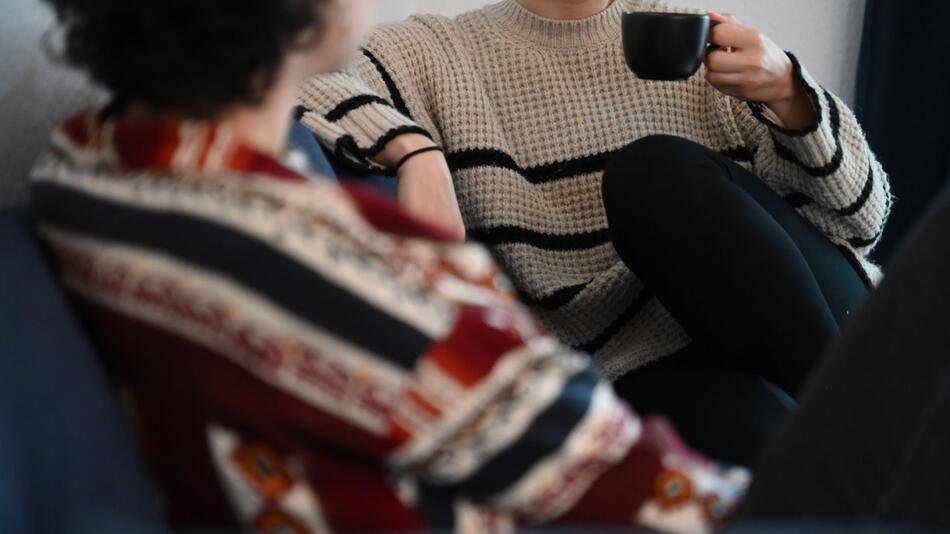 Zwei Frauen sitzen auf einem Sofa und unterhalten sich
