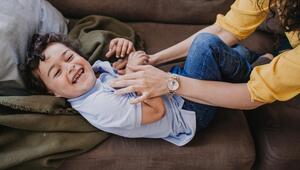 Mutter kitzelt Kind auf der Couch