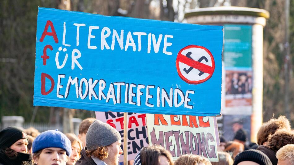 Bei einer Demo in München wird ein Plakat gegen die AfD in die Luft gehoben.