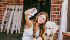 Ein Mädchen macht ein Selfie mit einem jungen Golden Retriever. Er schaut nicht in die Kamera.