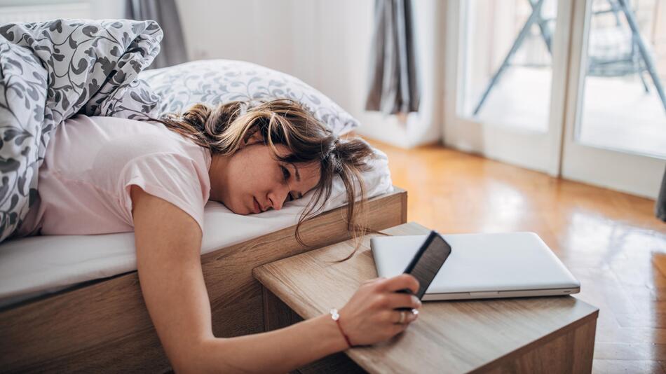 Frau mit Handy im Bett