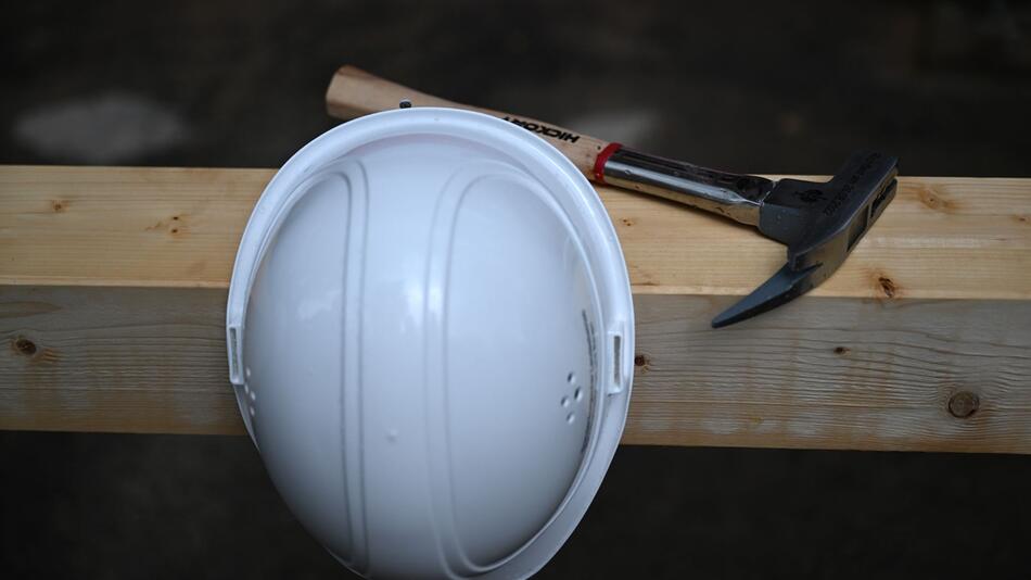 Bauhelm und Zimmermannshammer auf einer Baustelle