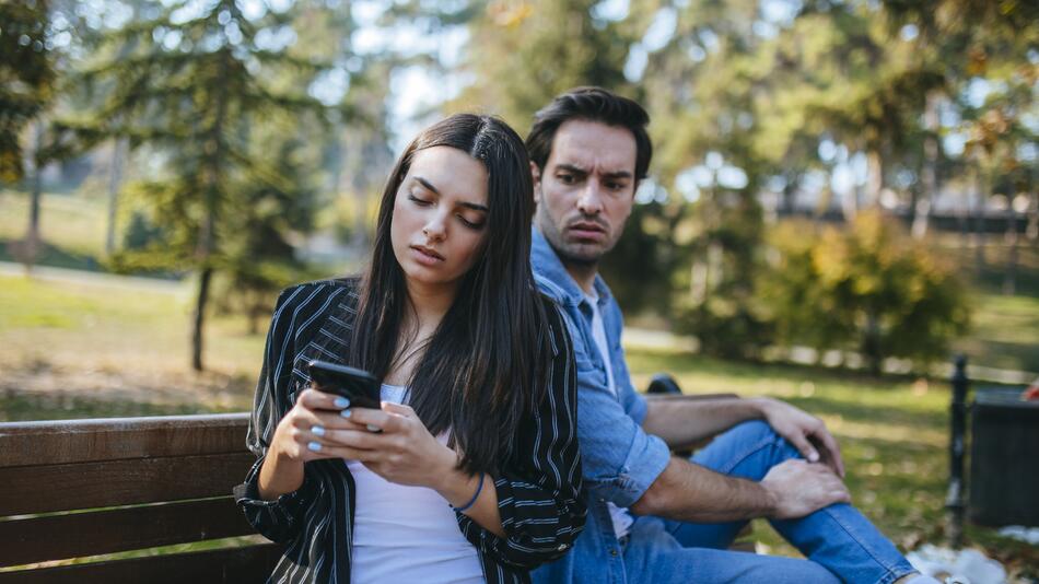 Frau guckt auf ihr Handy und Mann ist eifersüchtig