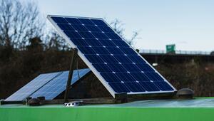 Zwei Solarpaneele, die auf einem grünen Dach montiert sind, vor einem Hintergrund mit kahlen ...