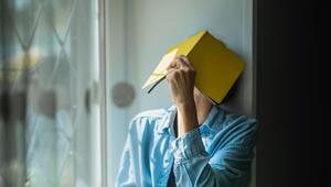 Eine Frau verbirgt ihr Gesicht hinter einem Notizheft