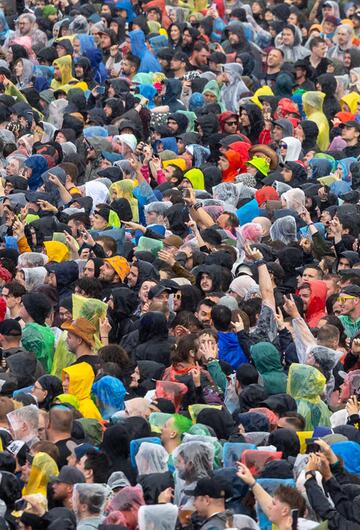 Festivalgäste in Regenkleidung stehen bei starkem Regen auf dem Gelände von Rock im Park in Nürnberg