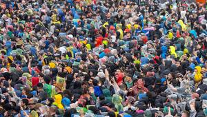Festivalgäste in Regenkleidung stehen bei starkem Regen auf dem Gelände von Rock im Park in Nürnberg
