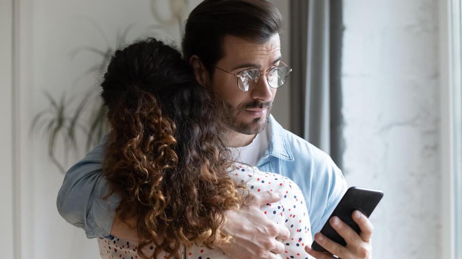 Ein Mann guckt verstohlen auf sein Handy.