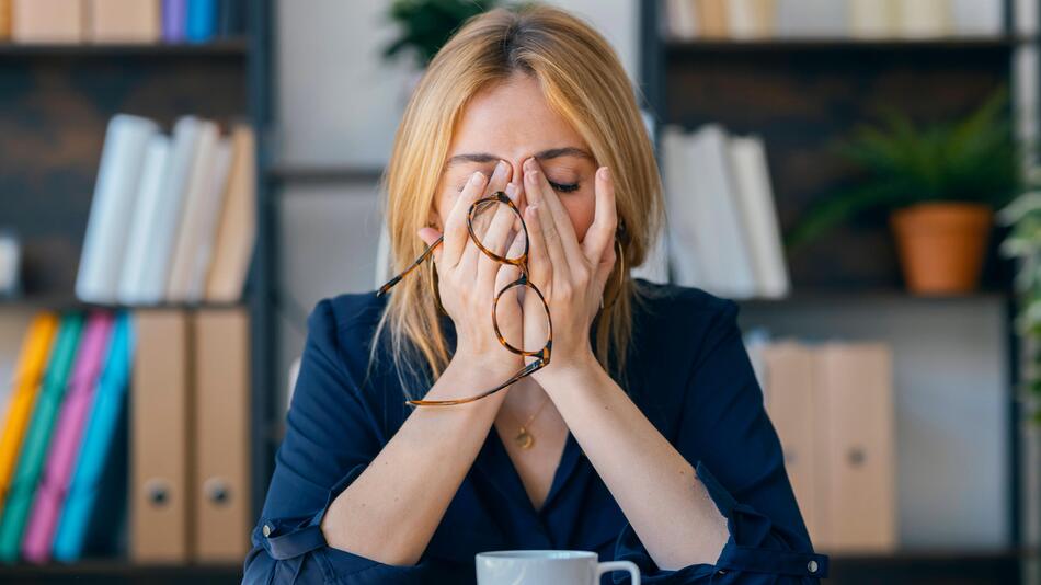 Frau sitzt müde an einem Tisch