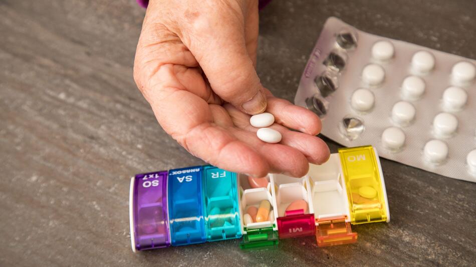 Seniorin nimmt Tabletten aus einer Pillendose
