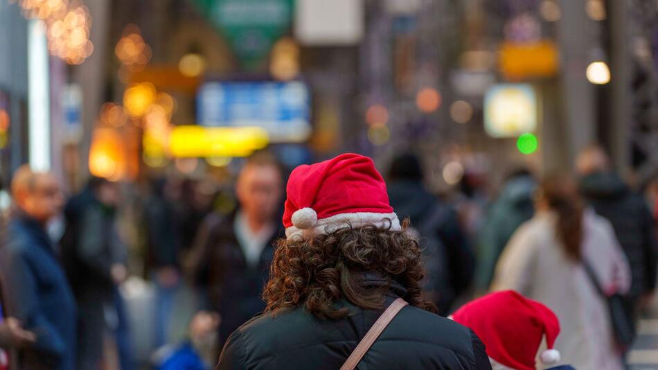 Eine Frau steht mit Weihnachtsmütze auf einem Bahnhof