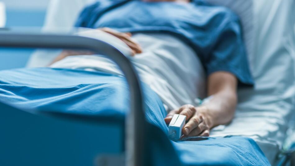 Patient in Krankenhausbett mit Pulsoximeter am Finger
